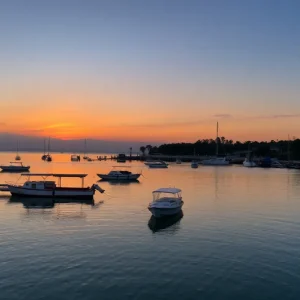 Serene waterfront with boats at sunset, peaceful atmosphere.